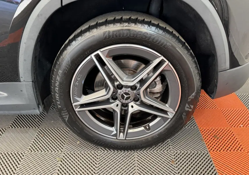 Gros plan sur la roue avant droite noire du Mercedes GLA 250 e AMG Line avec jante AMG à cinq branches.