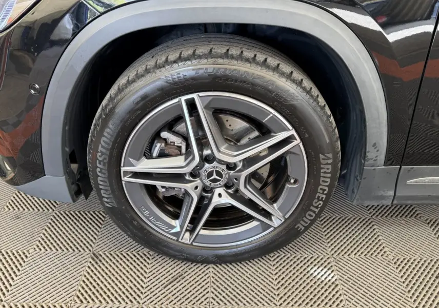 Gros plan sur la roue avant droite noire d’un Mercedes GLA 250 e AMG Line avec jante alliage cinq branches.