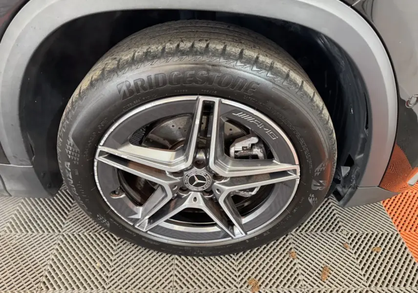 Gros plan sur la roue avant droite noire du Mercedes GLA 250 e AMG Line avec jante AMG cinq branches.