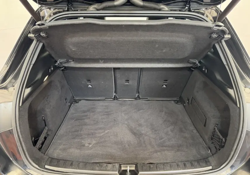 Coffre ouvert vu de l'arrière d'un Mercedes GLA 250 e AMG Line noir, montrant un espace de chargement propre et spacieux.
