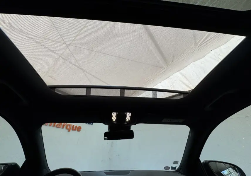 Vue intérieure du toit ouvrant panoramique du Mercedes GLA 250 e AMG Line noir, avec éclairage intérieur allumé.