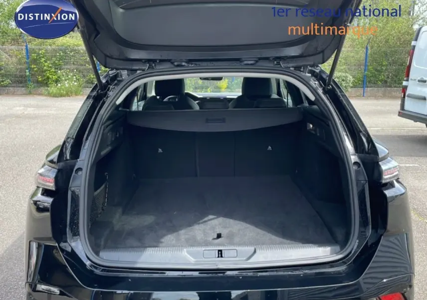 Coffre ouvert vu de l'arrière d'une Peugeot 308 SW noir métal, montrant un espace de chargement spacieux et propre.
