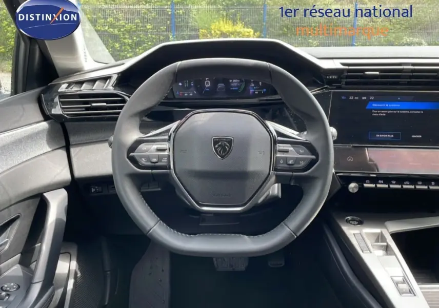 Vue intérieure centrée sur le volant noir de la Peugeot 308 SW Hybrid 2025 avec tableau de bord digital et console moderne.