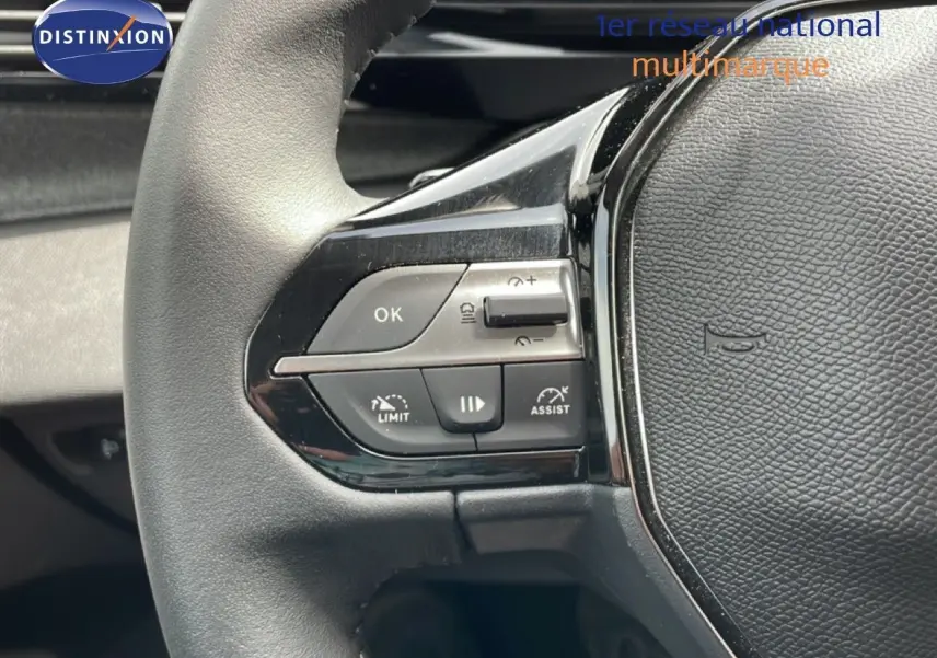 Gros plan sur le volant noir du Peugeot 308 SW Hybrid 145ch, montrant les commandes de régulateur et d'assistance.