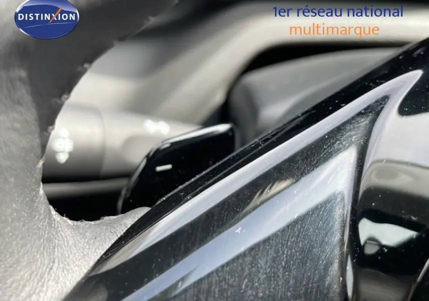 Gros plan sur le volant noir cuir et les commandes intégrées du Peugeot 308 SW Hybrid 2025.
