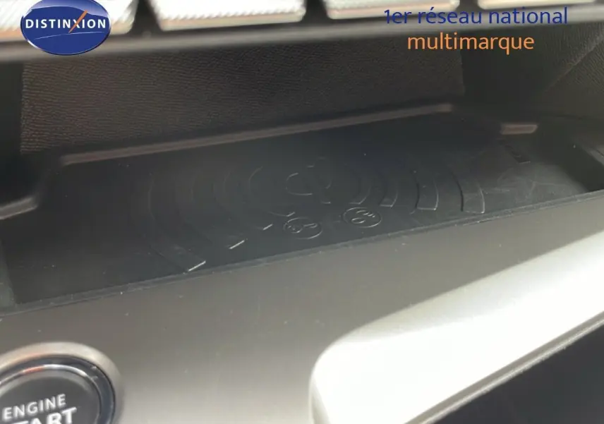 Gros plan sur la zone de recharge sans fil noire du tableau de bord de la Peugeot 308 SW Hybrid 2025.