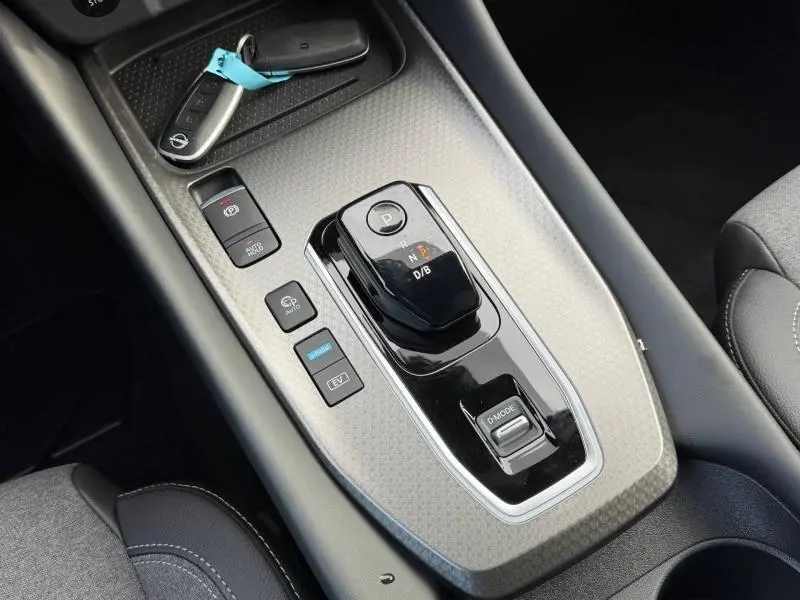 Gros plan sur la console centrale noire du Nissan Qashqai Hybrid e-POWER 2025 avec sélecteur de boîte auto et clés posées.