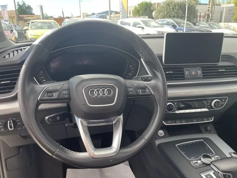 Vue intérieure centrée sur le volant Audi noir avec commandes, tableau de bord numérique et écran tactile du Q5 2017.