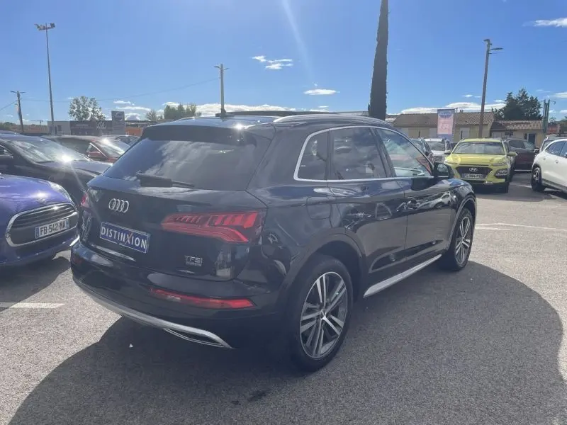 Audi Q5 2.0 TFSI 252 Avus noir métal vue 3/4 arrière droit sur parking ensoleillé.