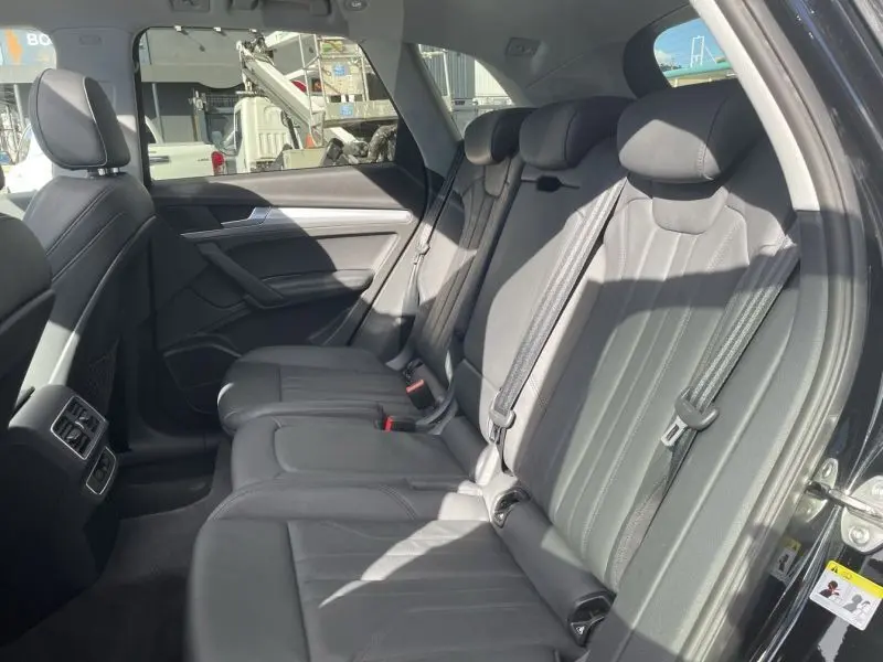 Vue intérieure côté droit des sièges arrière en cuir gris du SUV Audi Q5 noir métal de 2017, avec ceintures de sécurité visibles.