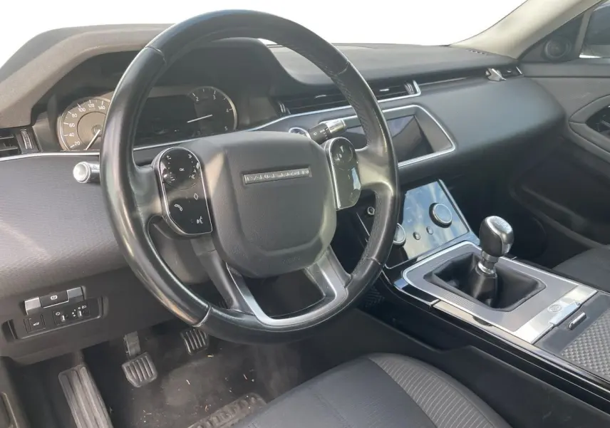 Intérieur du Range Rover Evoque 2020 blanc, vue côté conducteur sur le volant et la boîte manuelle noire.