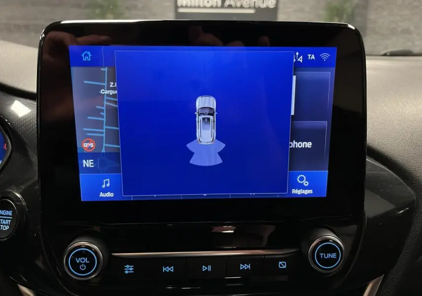 Écran tactile central du Ford Puma 2023 affichant l'aide au stationnement avec interface bleue et commandes audio.