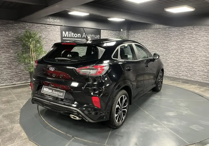 Vue 3/4 arrière droite du Ford Puma noir métallisé avec jantes alliage noires et sorties d'échappement chromées.