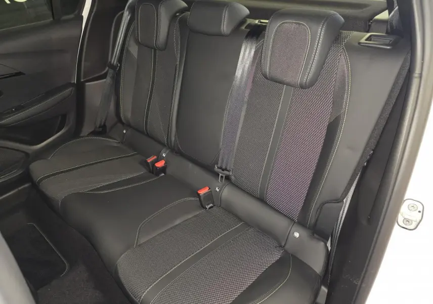 Vue intérieure côté droit sur la banquette arrière noire avec surpiqûres vertes de la Peugeot 208 blanche 2025.
