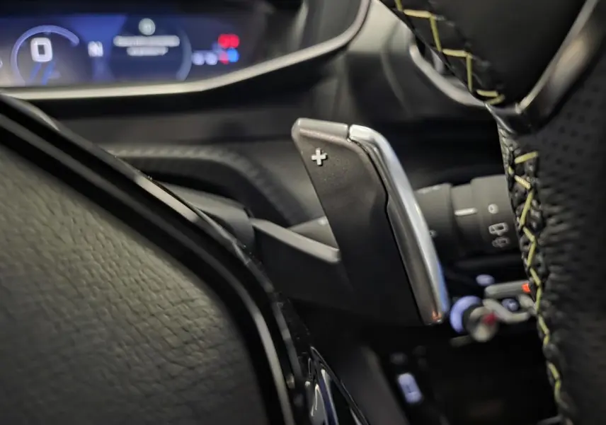 Gros plan sur la palette de changement de vitesse droite en aluminium et volant cuir perforé avec surpiqûres vertes Peugeot 208 GT.