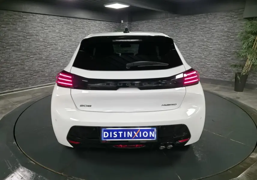 Vue arrière d'une Peugeot 208 blanche hybride 2025 avec feux arrière LED et bandeau noir brillant entre les feux.