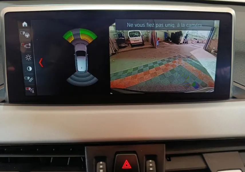 Écran central de BMW X1 sDrive18i 2021 montrant la caméra de recul et l’alerte de proximité en intérieur gris foncé.
