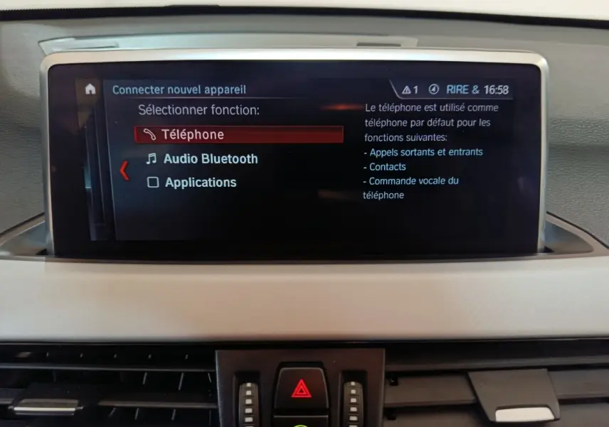 Écran central du tableau de bord de BMW X1 gris foncé, affichant le menu Bluetooth et téléphone.