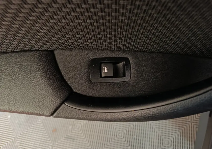 Bouton de commande de lève-vitre sur panneau de porte intérieur noir d'une BMW X1 sDrive18i Lounge 2021.