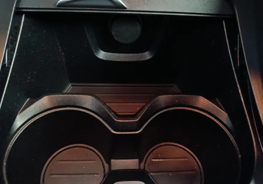 Gros plan sur les porte-gobelets noirs au centre de la console intérieure du BMW X1 sDrive18i Lounge gris foncé.