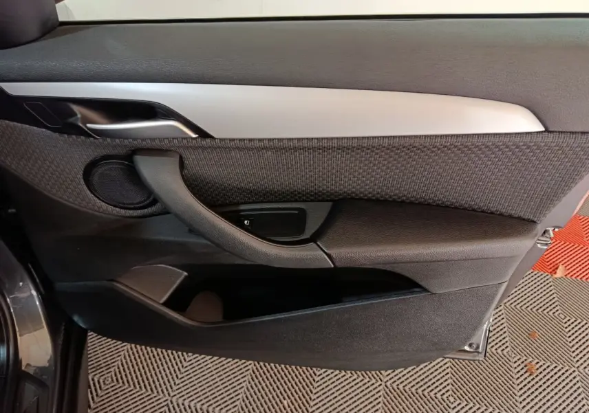 Vue rapprochée de la porte avant gauche du BMW X1 sDrive18i Lounge 2021 en gris foncé, avec garniture tissu et plastique noir.