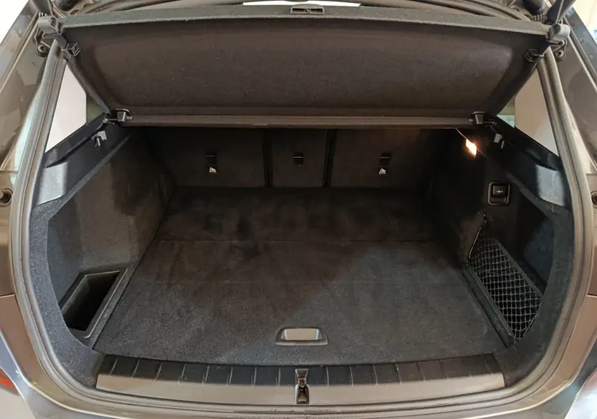 Coffre ouvert d’une BMW X1 sDrive18i Lounge gris foncé, vue de l’arrière montrant l’espace de chargement et le cache-bagages.