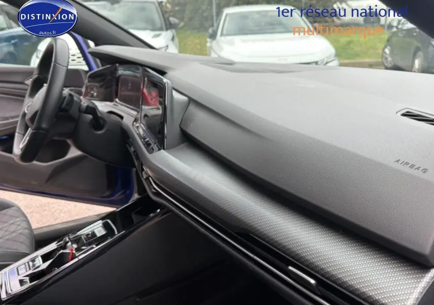 Vue intérieure côté passager de la Volkswagen Golf 2024 bleu, avec tableau de bord moderne et volant cuir visible.