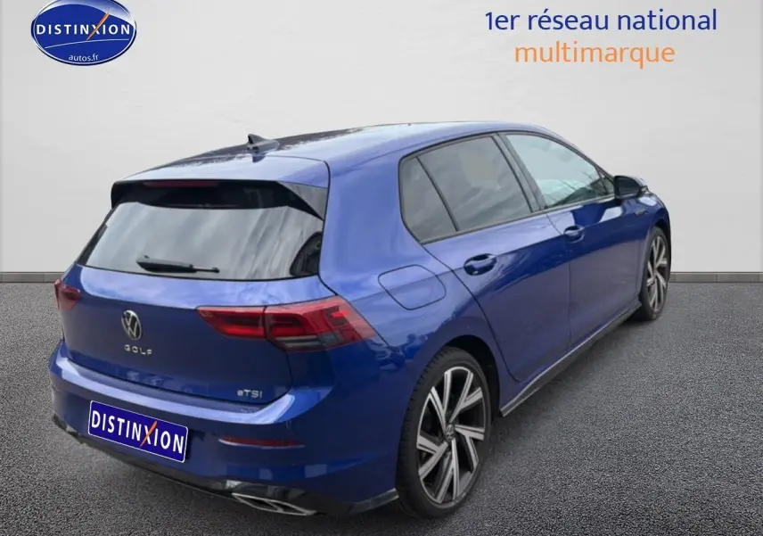 Vue 3/4 arrière droite d'une Volkswagen Golf 1.5 eTSI bleu avec jantes alliage et vitres arrière surteintées.