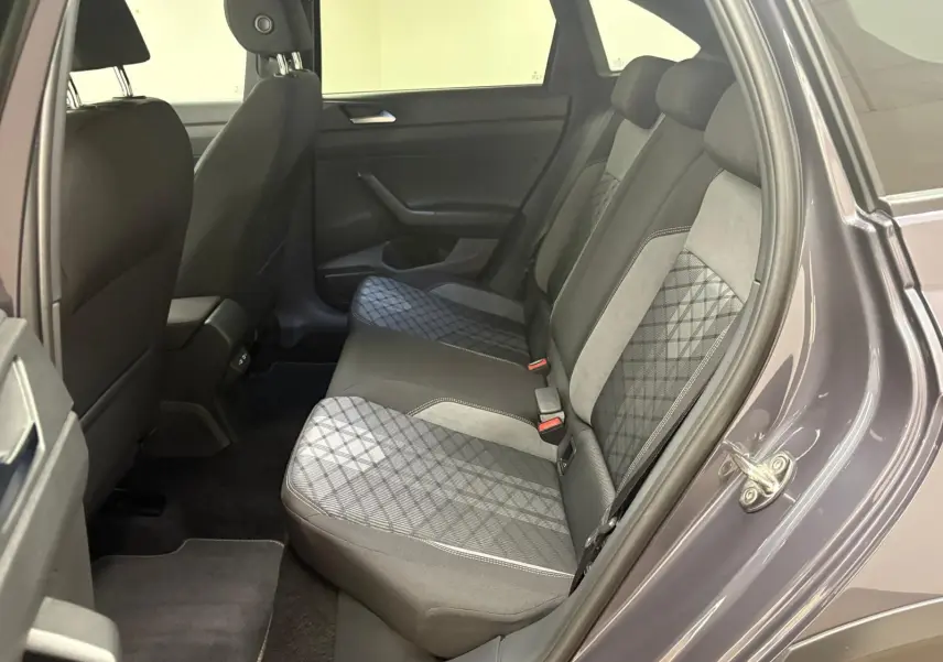 Vue intérieure arrière côté droit du Volkswagen Taigo gris cendré, montrant les sièges arrière en tissu à motif géométrique.