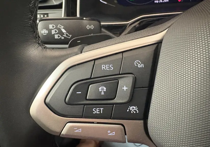 Gros plan sur les commandes au volant du Volkswagen Taigo 2024, boutons de régulateur de vitesse et assistance au maintien de voie.