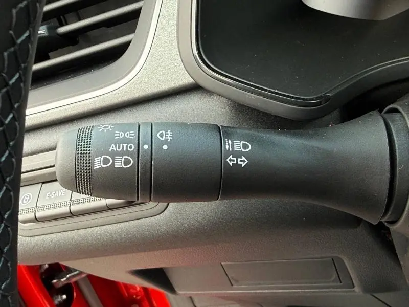 Gros plan sur la commande des feux et clignotants à gauche du volant dans un Renault Captur rouge 2025.