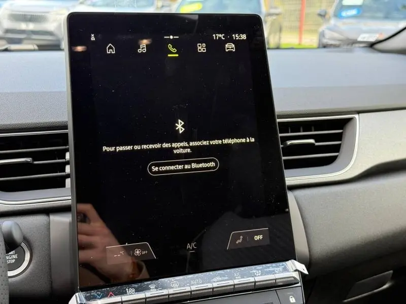 Vue rapprochée de l'écran tactile central noir du tableau de bord du Renault Captur rouge 2025, affichant la connexion Bluetooth.