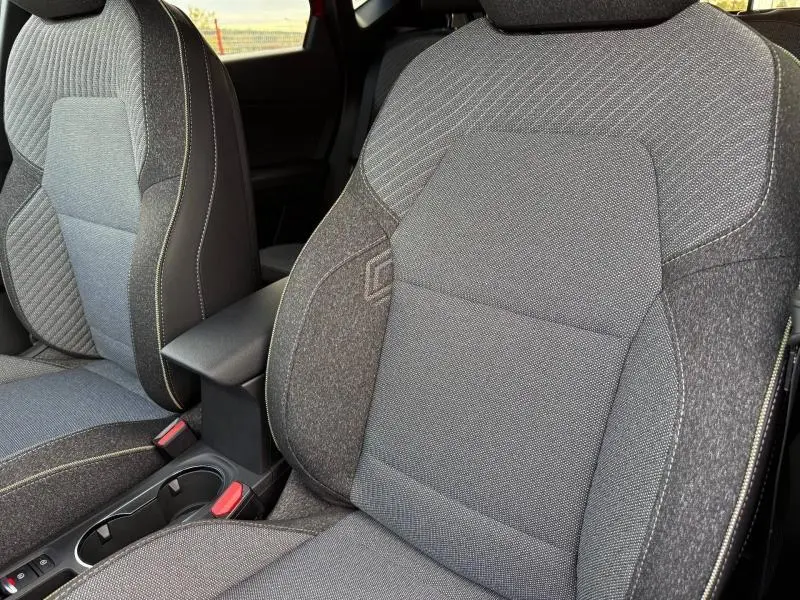 Gros plan sur les sièges avant gris du Renault Captur 2025, avec accoudoir central et coutures contrastées.
