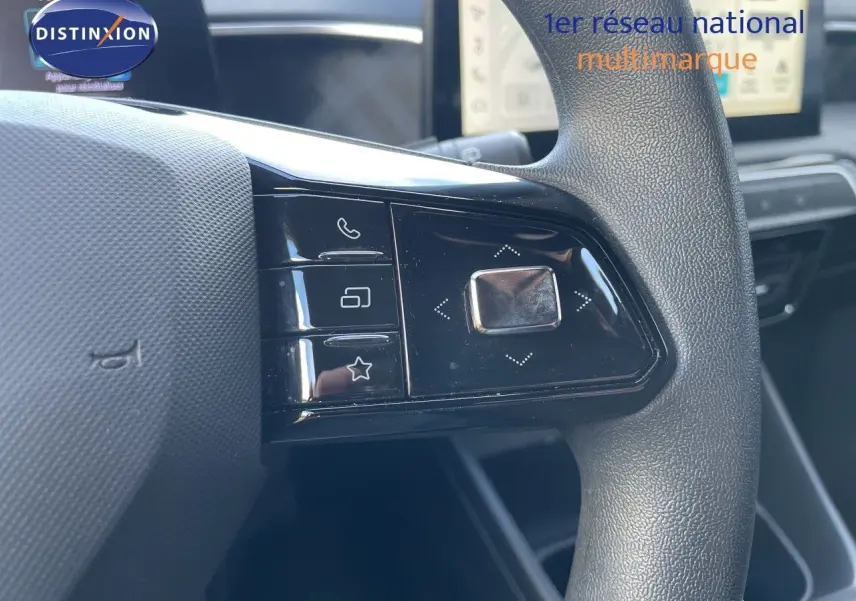 Gros plan sur les commandes gauche du volant noir texturé du MG3 2024, avec boutons multifonctions et écran tactile en arrière-plan.
