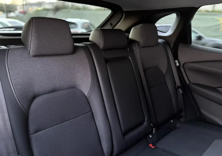 Vue latérale des sièges arrière noirs du Nissan Qashqai 2025, montrant les appuie-têtes et ceintures de sécurité.