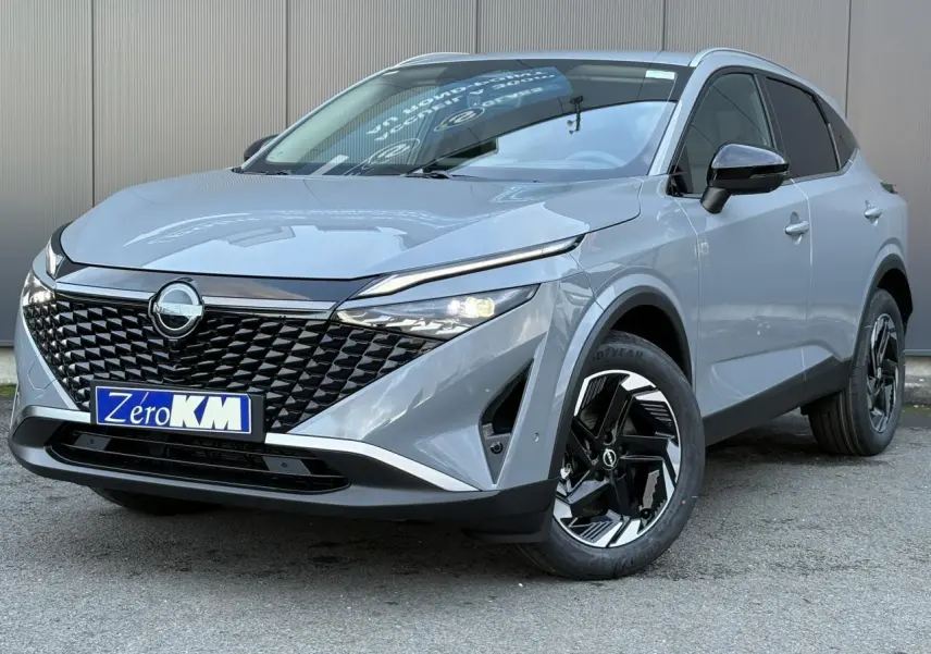 Vue 3/4 avant droit du Nissan Qashqai III gris Ceramic avec calandre noire et jantes alliage bicolores.