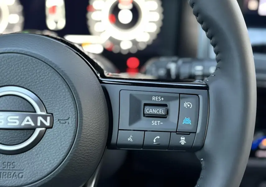 Gros plan sur le côté droit du volant cuir noir du Nissan Qashqai 2025 avec commandes de régulateur et aides à la conduite.