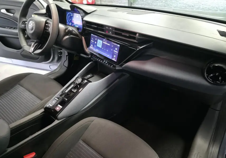 Vue intérieure côté conducteur de l'Alfa Romeo Junior 1.2 Ibrida 2025, avec écran tactile et volant multifonctions noir.