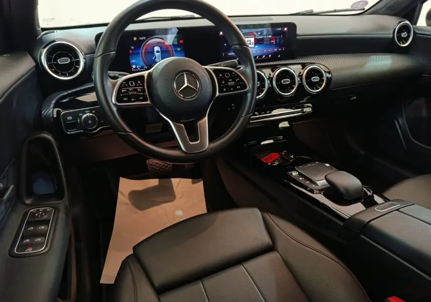Vue intérieure de face du poste de conduite de la Mercedes Classe A 200 Business Line noire avec écran tactile et volant cuir multifonctions.