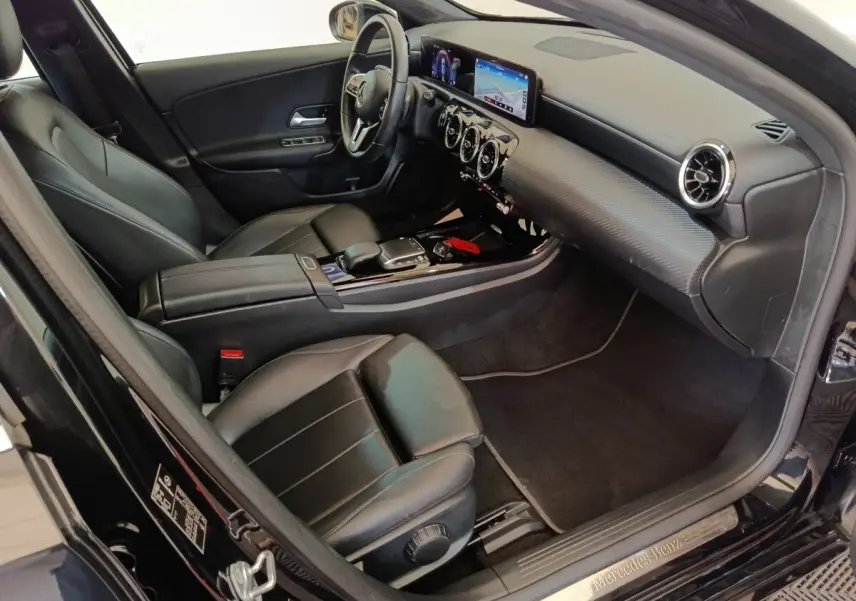 Vue intérieure côté conducteur de la Mercedes Classe A 200 Business Line 2021 noire, avec tableau de bord numérique et sièges cuir noirs.