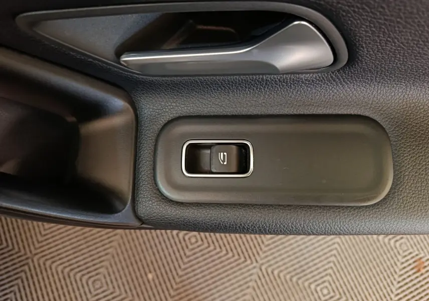 Gros plan sur la commande de verrouillage de porte côté gauche dans l'habitacle noir d'une Mercedes Classe A 200 Business Line.