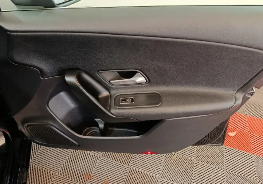 Vue intérieure côté gauche de la porte avant noire d'une Mercedes Classe A 200 Business Line avec poignée et commande de vitre.