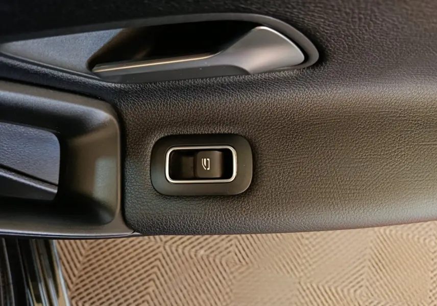 Gros plan sur le bouton d'ouverture de coffre intégré à la garniture intérieure noire d'une Mercedes Classe A 200 Business Line.