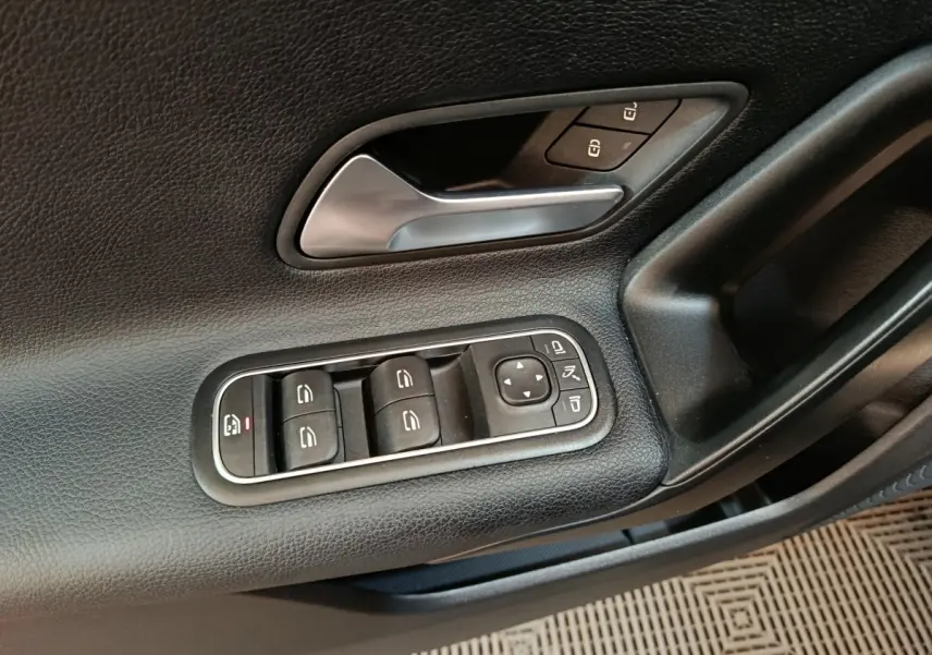Gros plan sur la porte côté gauche noire de la Mercedes Classe A 200 Business Line avec commandes de vitres et rétroviseurs.