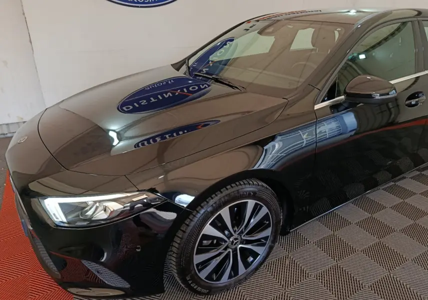 Vue 3/4 avant droit d'une Mercedes Classe A 200 Business Line noire avec jantes alliage et phares LED allumés.