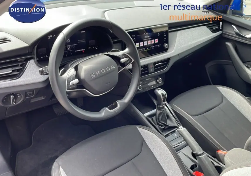 Vue intérieure côté conducteur de la Skoda Scala 2025, volant multifonction et sellerie tissu gris et noir.