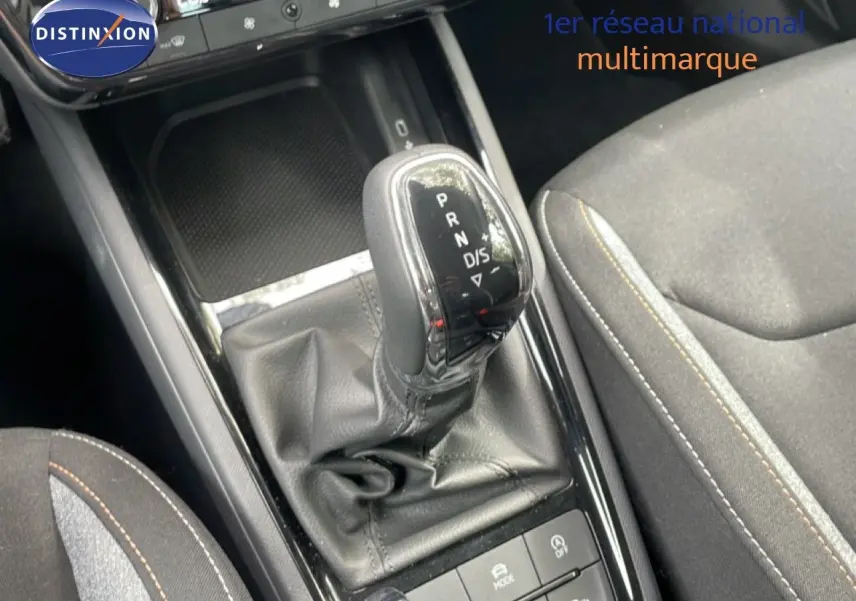 Gros plan sur la commande de boîte automatique et la console centrale du Skoda Scala 2025 en tissu gris avec surpiqûres contrastées.