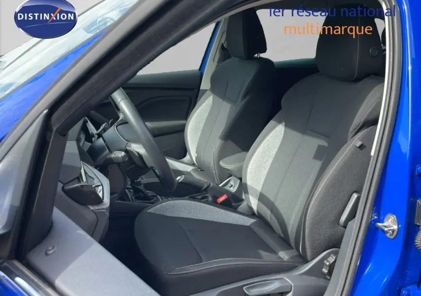 Vue intérieure côté conducteur d'une Skoda Scala bleu racing metal, sièges tissu gris et noir avec surpiqûres.