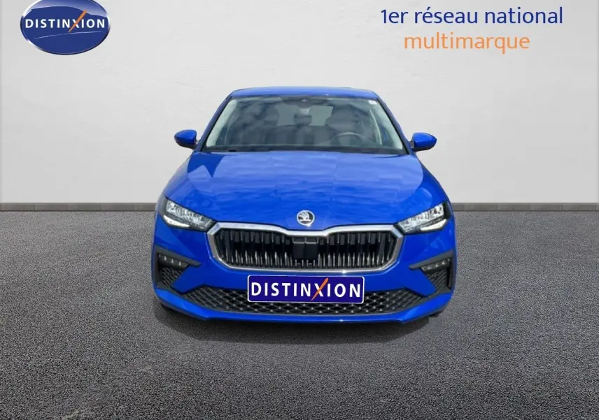 Vue frontale d'une Skoda Scala 2025 bleu racing metal avec calandre noire et phares LED allumés.
