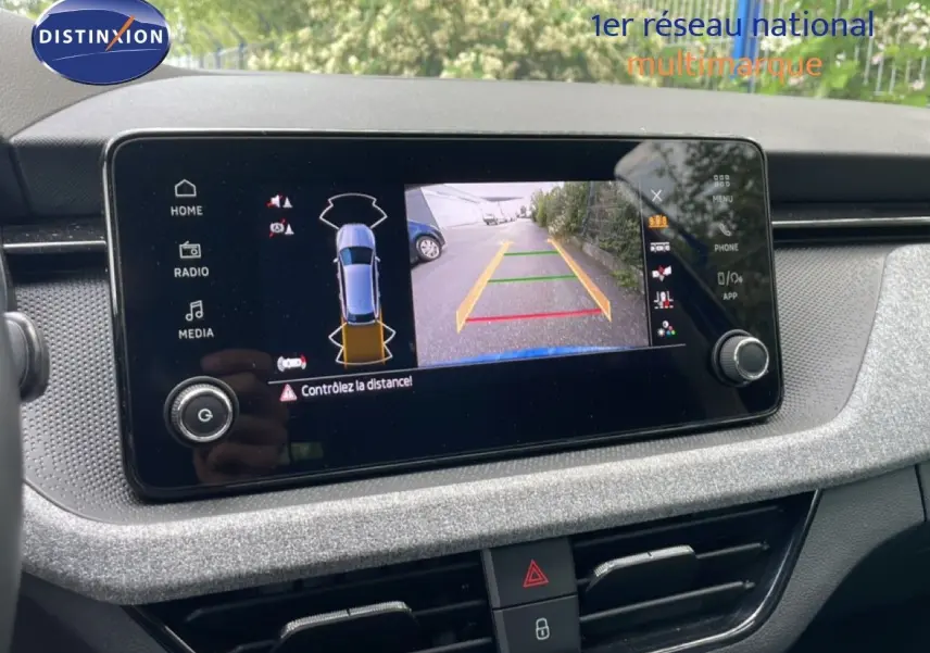 Écran central de la Skoda Scala bleu racing montrant la caméra de recul avec guidage de trajectoire.